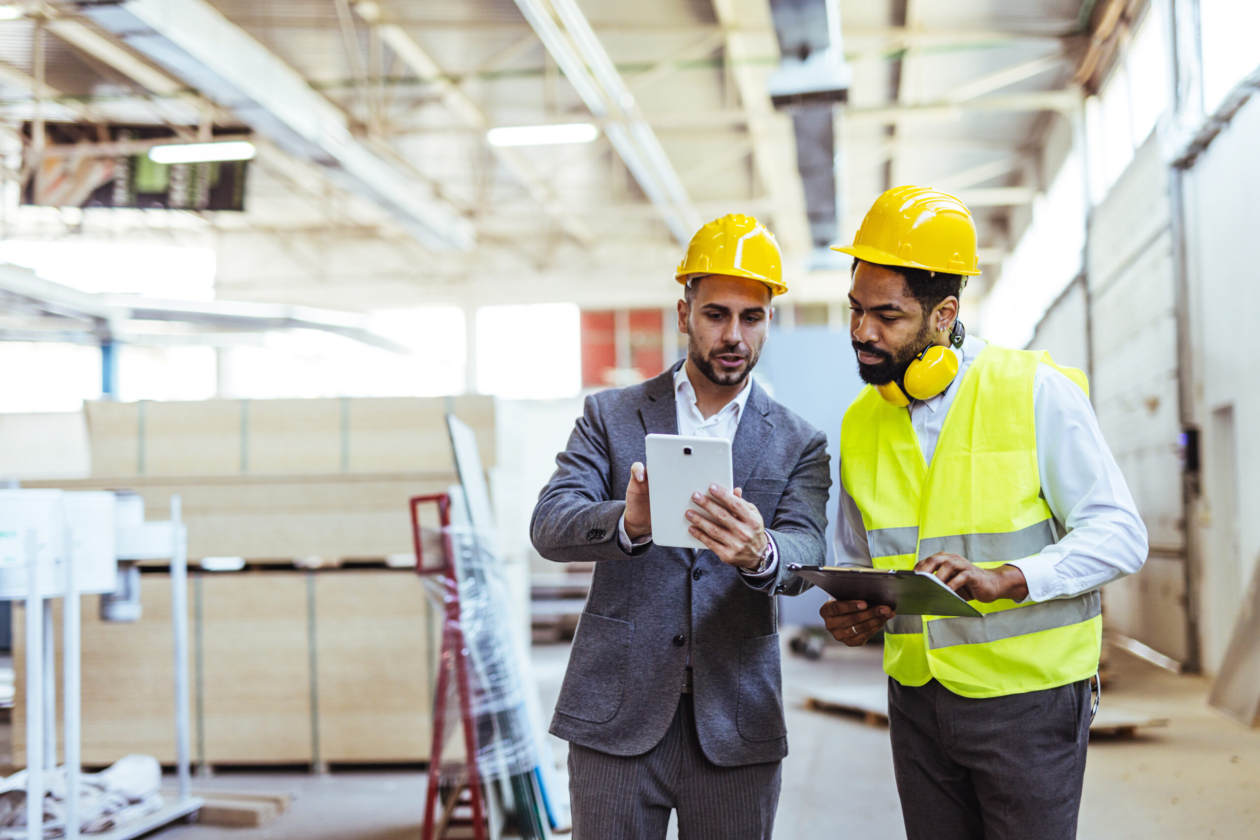 Two Engineers Discussing Plans on a Construction Site With Digital Devices
